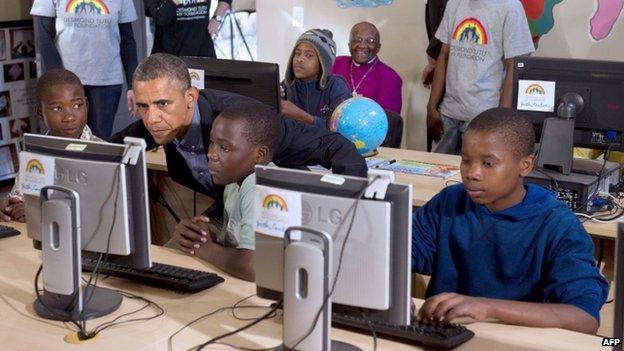 US President Barack Obama (2L) sits down at a computer as he tours a classroom at the Desmond Tutu HIV Foundation Youth Centre in Cape Town, South Africa, on 30 June 2013