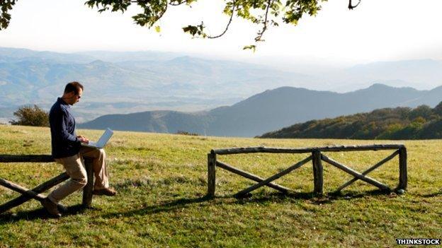 A man on his laptop in the countryside