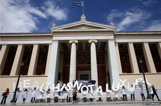 Members of the French medical charity Medecins du Monde (MDM, Doctors of the world) hold letters reading 'health is not a luxury ' outside the University of Athens