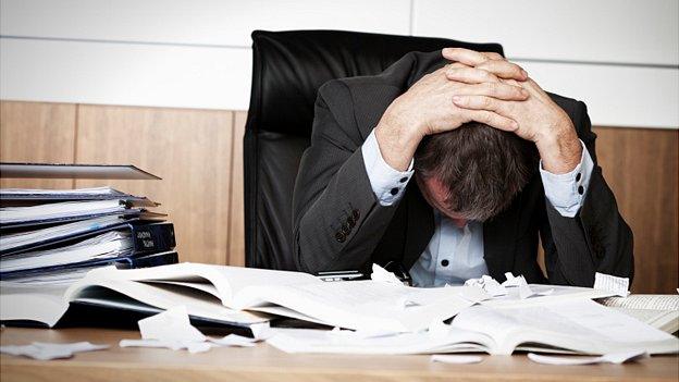 Man holds his head at his desk