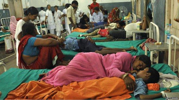 A mother rests with her sick son in a hospital in Patna on 17 July 2013