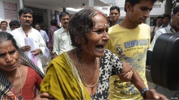 A crying woman is escorted after her grandson died at a hospital in the city of Patna on 17 July 2013