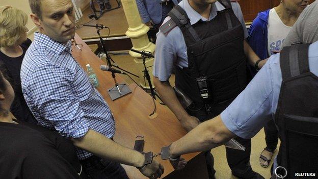 Russian protest leader Alexei Navalny (L) is handcuffed and escorted by Interior Ministry officers in a courtroom in Kirov, July 18, 2013