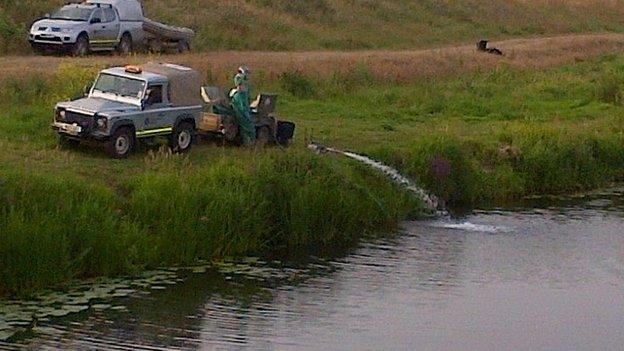 Environment Agency staff treating the river at Welney in Norfolk