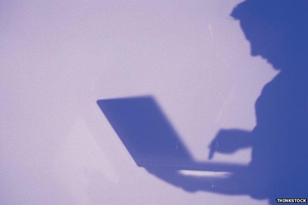 Man in silhouette looking at laptop