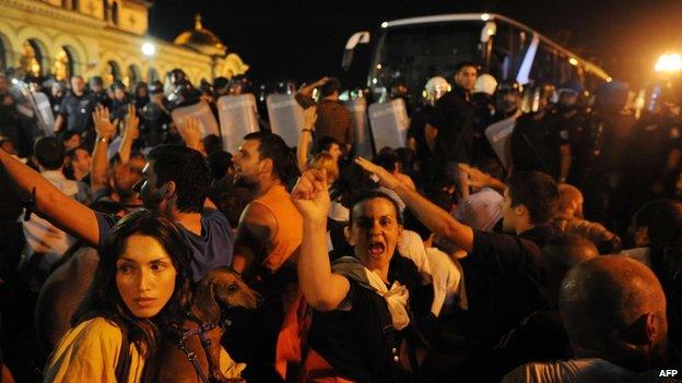 Anti-government protestors shout at riot policemen trying to escort a bus from the parliament in Sofia