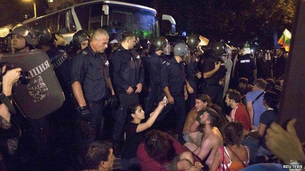 Protesters try to stop a heavily guarded bus trying to get deputies out of the parliament