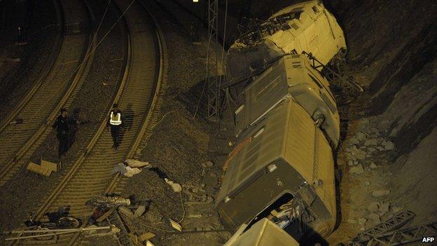 Spanish police officers walk next to derailed cars at site of train accident near Santiago de Compostela on 25 July 2013