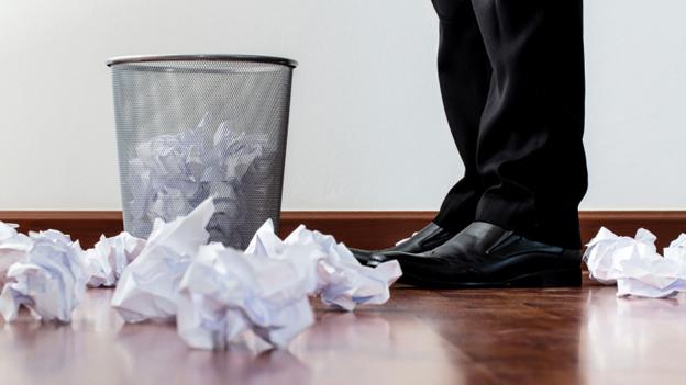 Scrunched waste paper by someone's feet