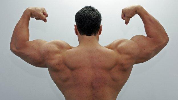 A view from behind of a man flexing his muscles