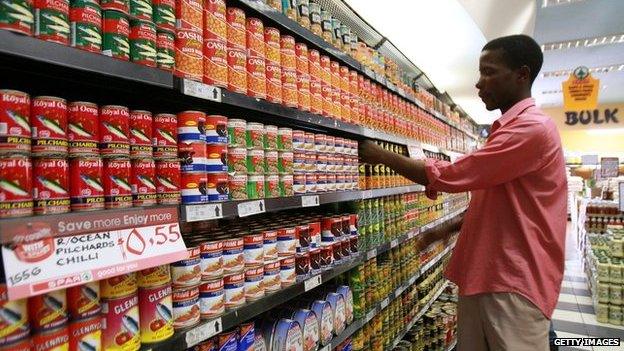 A shop worker arranging cans in a Harare supermarket