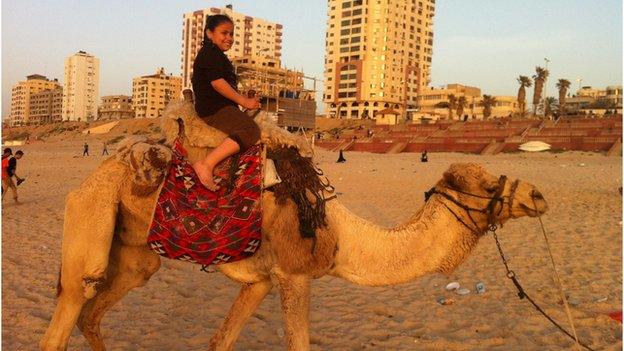 Child rides a camel on the beach in the Gaza strip