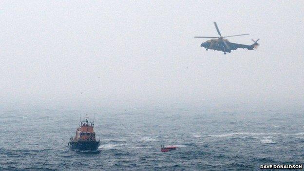 Rescuers approaching a life raft from the crashed helicopter