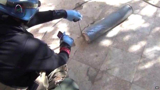 Still from amateur video posted online shows a presumed UN staff member measuring and photographing a canister in the suburb of Muadhamiya in Damascus on 26 August 2013