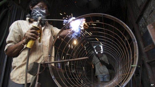 An Indian man works at a welding workshop in Ahmedabad, India, Thursday, Aug. 22, 2013