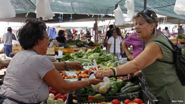 A woman receives a bag of fruits at the Malveira village market on the outskirts of Lisbon August 29, 2013.