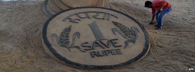 A rupee coin sketched in sand