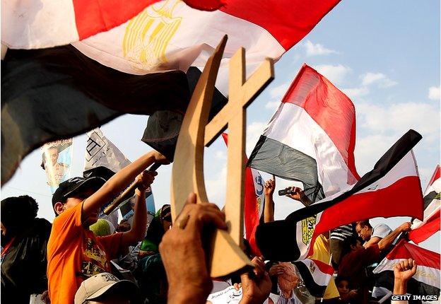 Egyptians hold up sign of cross and crescent - symbolising Christians and Muslims