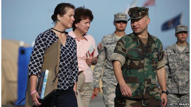 Illustrator Janet Hamlin and others walk across a compound at Guantanamo