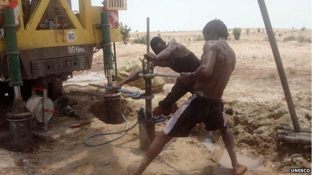 Technicians install a submersible pump in a borehole prior to test pumping, Turkana, Kenya