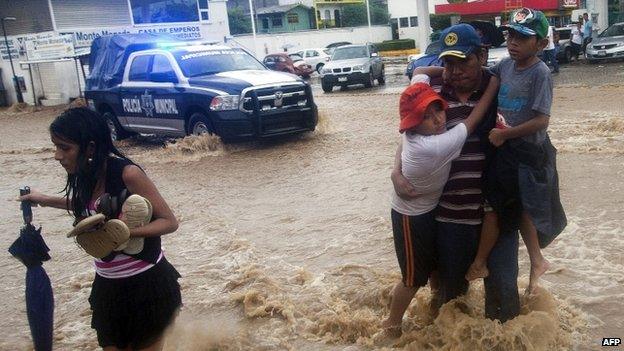 A family wades through a flooded street in Acapulco, Guerrero state, following the passage of Tropical Storm Manuel on 15 September, 2013.