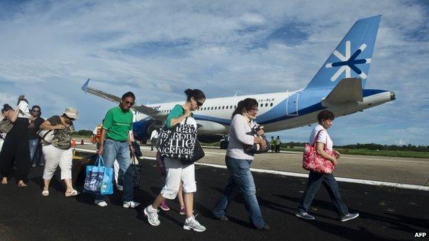 Tourists waiting their flight to Mexico City, walk at the airport of Acapulco, Guerrero state, Mexico, on 17 September, 2013 flooded by heavy rains that have been hitting the country.