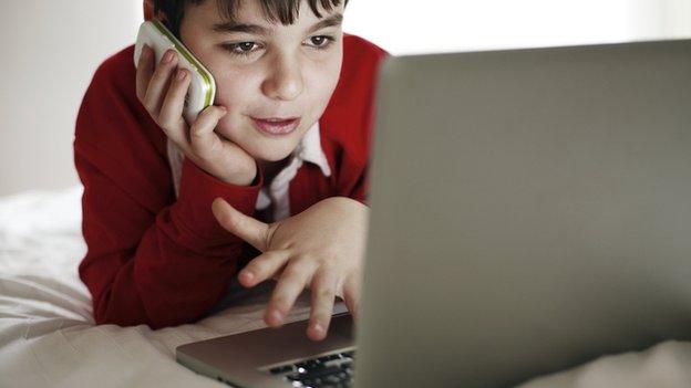 A boy with a laptop and a smartphone