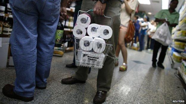 People wait in line as they buy toilet paper in a supermarket in Caracas 17 May, 2013.