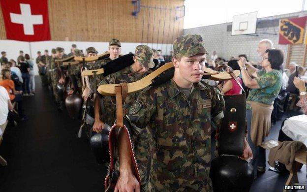 Recruits from the veterinary troops of the Swiss Army play traditional cow-bells during an official visiting day at a Swiss army base in Sand bei Schoehnbuehl, outside Bern 7 September, 2013.