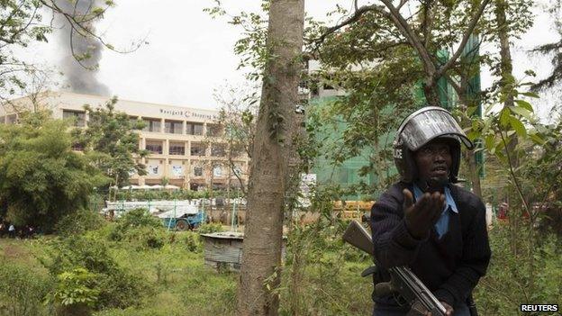 A security officer gestures as smoke rises from Westgate Shopping Centre