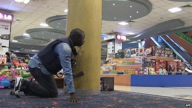 A member of the security team holds a gun as he hides behind a pillar