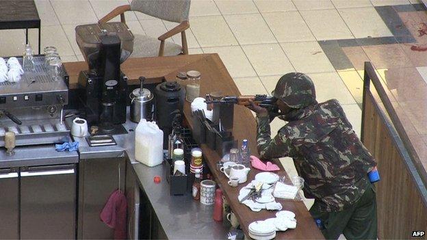 A soldier aims his gun while he leans on a coffee bar