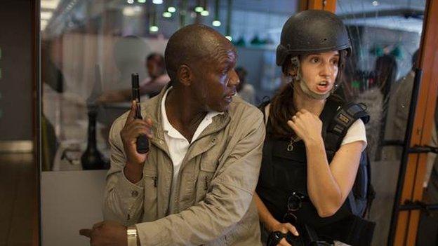 Nichole Sobecki inside the mall with a security officer - she is wearing a helmet and bullet proof vest