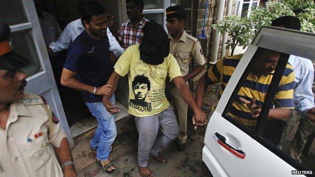 Police officers escort a man (face covered) arrested in connection with the gang rape of a photo journalist in Mumbai