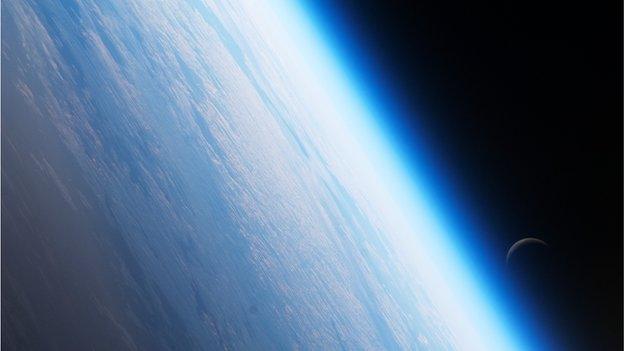 The Moon hovers Earth's atmosphere as seen from the International Space Station