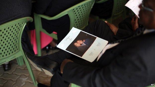 A man sits with the service leaflet during the funeral of Mbugua Mwangi and his fiancee Rosemary Wahito, in Nairobi, Kenya, Friday 27 September 2013