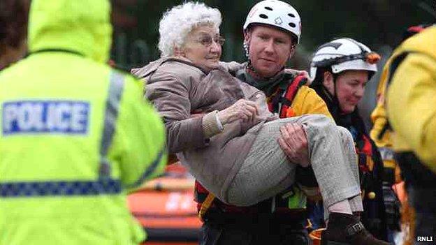 Volunteer Bryn Harrison helping an elderly woman in the floods in St Asaph in November 2012