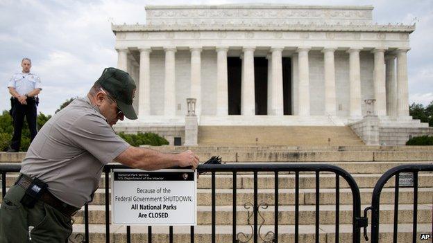 A US Park Police officer watches at left as a National Park Service employee posts a sign on a barricade closing access to the Lincoln Memorial in Washington on 1 October 2013.