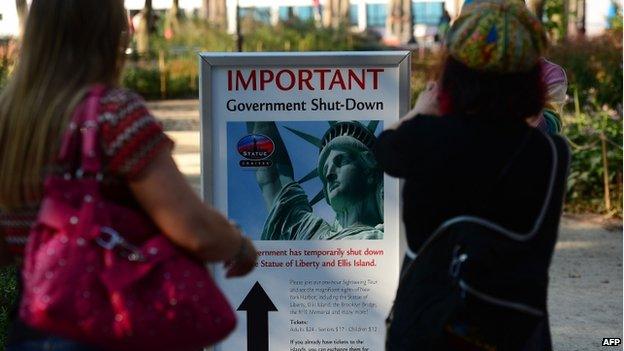 Tourists look at a sign announcing that the Statue of Liberty is closed due to a US government shutdown in New York, on 1 October 2013.