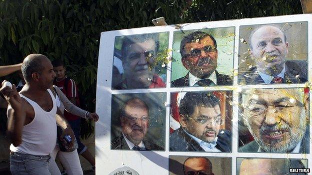 An anti-government protester throws an egg at a poster of Tunisian politicians, including Prime Minister Ali Larayedh (top row, C) and leader of the Islamist Ennahda movement Rached Ghannouchi (centre row, R) during a demonstration in Tunis, 2 October, 2013.