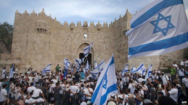Israeli youths hold their national flag as they take part in the "flag march" through Damascus Gate in Jerusalem's old city during celebrations for Jerusalem Day on 8 May, 2013.
