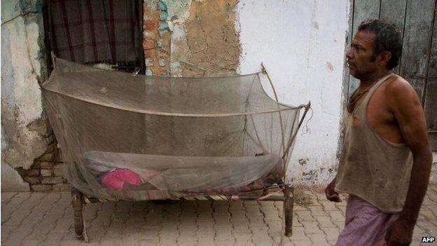 A woman sleeping under a mosquito net in Delhi