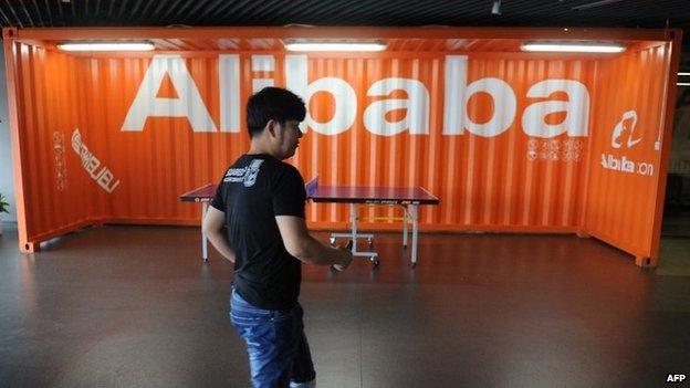 Employee walks past Alibaba sign