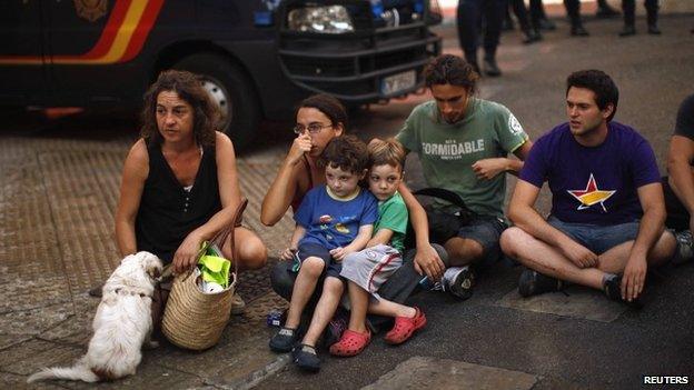 Carolina Gonzalez (L) and her three- and four-year-old children sit in a street with activists after riot police evicted them from an unoccupied building in Malaga, southern Spain, 3 October