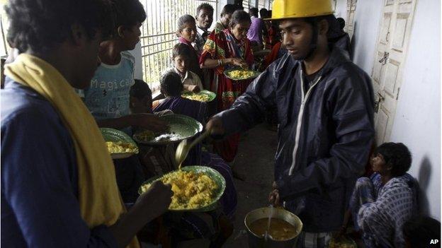 Indian villagers are given food at a shelter in Ganjam district, east of Bhubaneswar, 12 October 2013