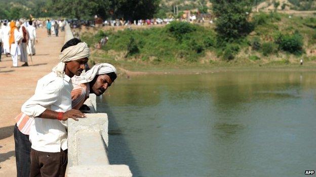 Hindu pilgrims look down at the Sindh river as they stand on the bridge where a deadly stampede took place the previous day on October 14, 2103