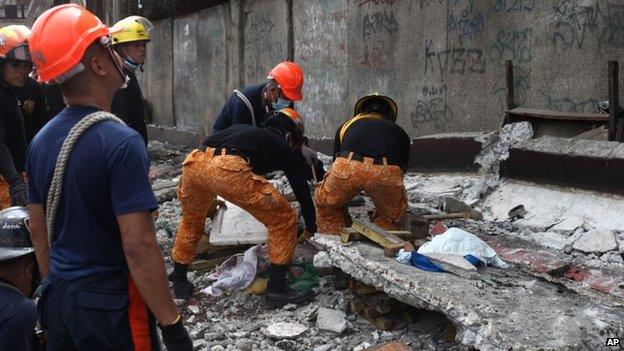 Rescuers shift through the rubble to recover an unidentified man at a fish port in Pasil, Cebu, central Philippines, 15 October 2013
