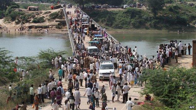 Indian police and bystanders gather on a bridge where Hindu devotees were crushed in a stampede outside the Ratangarh Temple at Datia district in central Madhya Pradesh state on October 13, 2013