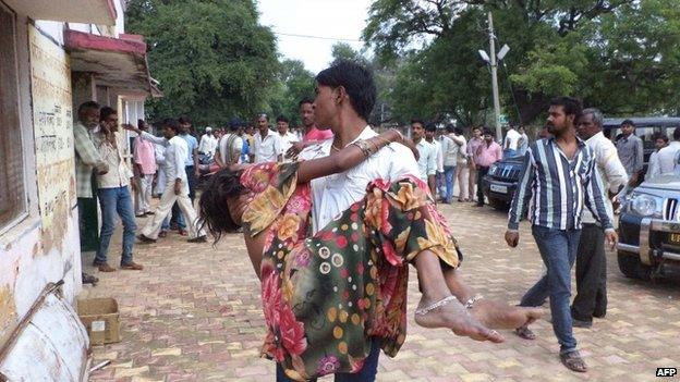 An Indian man carries a Hindu devotee injured in a stampede outside the Ratangarh Temple