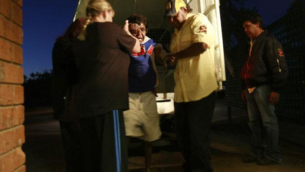 Staff members (R) of the Tangentyere night patrol and of an alcohol centre (L) assist an intoxicated Aboriginal woman in the central Australian town of Alice Springs in this picture taken July 5, 2007